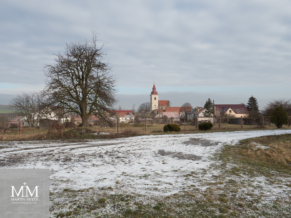 Vesnice v zimě, v pozadí barokní kostel. Fotografie vytvořena objektivem Olympus 12 - 40 mm 2.8 Pro.